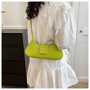 Detailed view of neon green leather underarm bag with gold crescent buckle on person