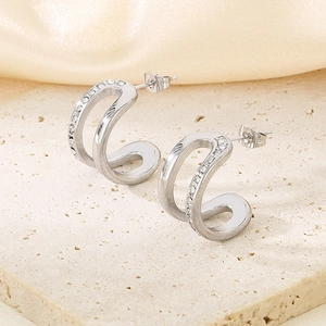Macro shot of silver C-shaped double hoop earrings with sparkling rhinestones on stone base