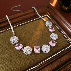 Detailed macro view of silver necklace with pink square zircon flower pendant on velvet
