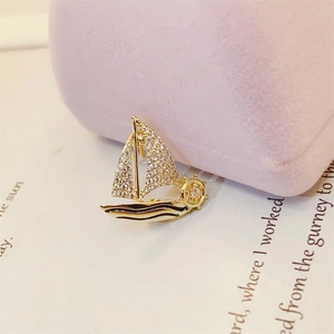 Macro shot of gold sailboat brooch with sparkling crystals and fine metal detailing