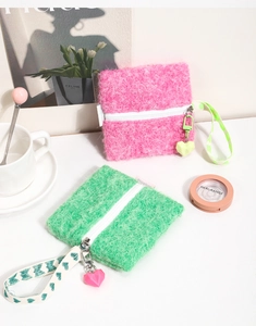 Close-up of plush square coin purse with heart pendant and printed wrist strap