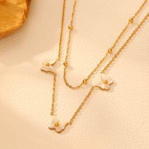 Detail of layered gold necklace featuring elegant white mother-of-pearl butterfly pendants