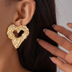 Close-up of gold hollow heart earring with lava texture on model for a vintage look