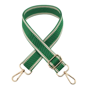 Detail of green and beige herringbone woven bag strap with golden metal buckles