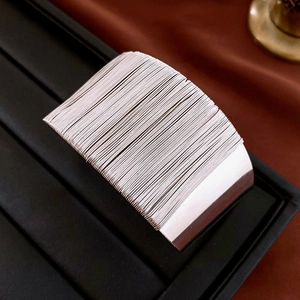 Macro shot of wide silver multi-line textured bangle on a black jewelry display tray