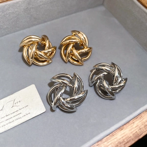 Close-up of golden and silver woven hollow star vortex stud earrings on a display tray