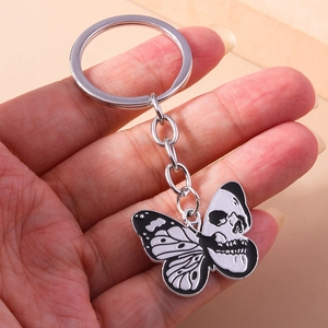 Detailed view of a gothic skull butterfly keychain held in hand with metal link chain