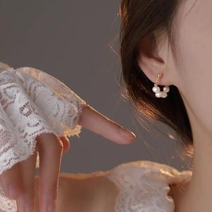 Elegant beaded baroque pearl earrings in gold finish worn by a model in soft sunlight