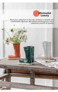 Rain boot-shaped ceramic vases in orange, white and green on a wooden staircase