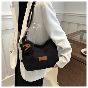 Detail view of black corduroy tote bag with fashion label and small round pouch accessory