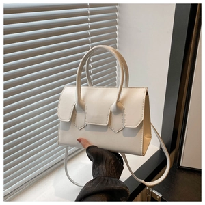 Close-up of a white leather handbag featuring dual handles and a detachable shoulder strap