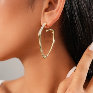 Chic gold twisted bamboo earrings with crystal accents worn by a model in soft lighting