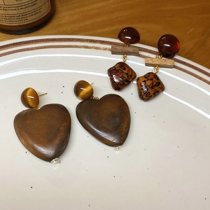 Gros plan de boucles d'oreilles cœur en bois et résine léopard sur un plateau en céramique