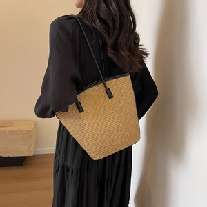 Minimalist striped woven straw beach tote bag with black leather shoulder straps on model