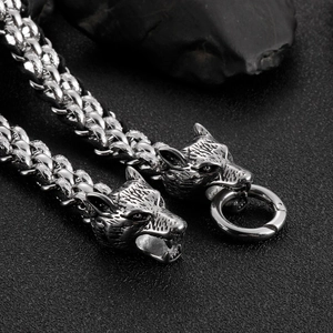 Macro shot of silver dual wolf head buckles on a braided leather cord bracelet