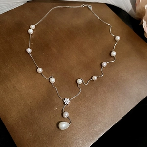 Detail of silver pearl necklace with floral zircon pendant and teardrop drop pearl
