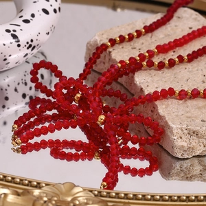 Detail of red faceted crystal beads and gold metal spacers on a multi-strand necklace