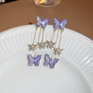 Detail of purple butterfly tassel earrings with crystals on a white carved plate