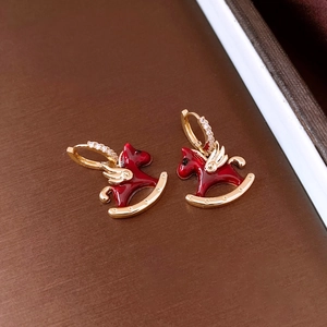 Macro detail of red enamel horse earrings with gold plating and sparkling zircon stones