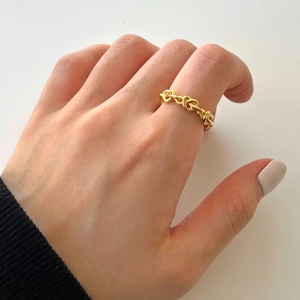 Detailed close-up of a gold heart-shaped chain ring worn on a finger in a 45-degree view
