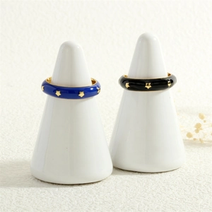 Close-up of enamel star rings in blue and black colors on white display cones