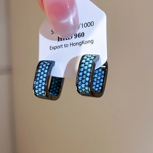 Macro detail of black hoop earrings featuring three rows of teal turquoise stones