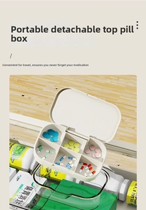 Top view of white 6-compartment medicine box organizer with pills on a wooden desk
