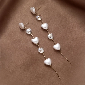 Detail of vintage long drop earrings with artificial pearls and heart-shaped crystals