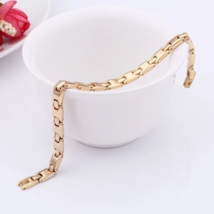 Detail of a polished gold titanium steel link bracelet on a white ceramic mug