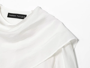 Close-up of a white cotton-linen neckline showing the brand label and fabric texture