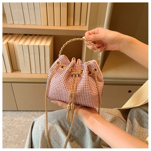 Detailed close-up of pink rhinestone bucket bag with golden tassel drawstring and metal handle