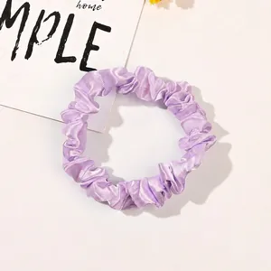 Detailed macro view of pink satin scrunchie with smooth silk-like texture and soft pleats
