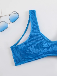 Detailed view of bright blue bikini top featuring textured smocking fabric and wide straps
