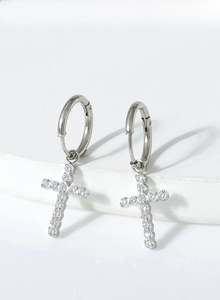 Detail of silver titanium steel cross hoop earrings with white zircon on stone background