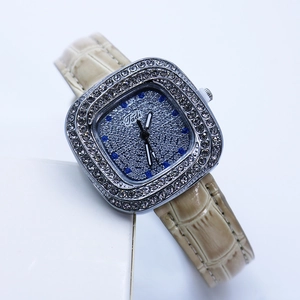 Detail of square watch dial with blue and clear rhinestones and beige leather strap