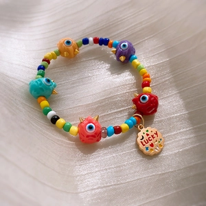 Detail of colorful ceramic bracelet with monster eye beads and a metal lucky tag charm