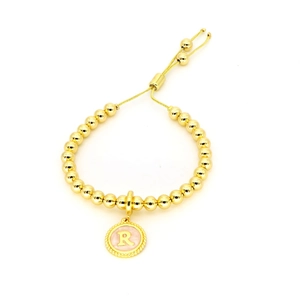 Detail van de 18k vergulde kralenarmband met verstelbare sluiting en roze bedel letter R