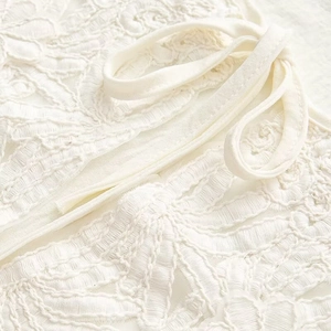 Macro detail of white floral embroidery lace fabric with matching drawstring cords
