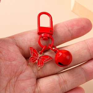 Chic red metal keychain featuring a butterfly pendant and a round bell charm on a bag