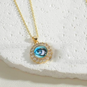 Macro shot of gold necklace with blue evil eye pendant and white zircon inlay