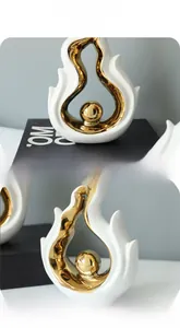 Detail of modern white and gold ceramic sculpture featuring a central golden sphere accent