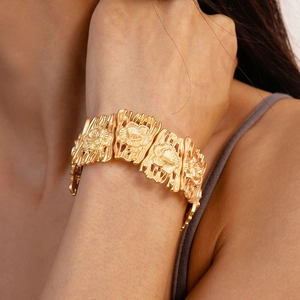 Detail of matte gold cuff bracelet featuring embossed 3D floral geometric patterns