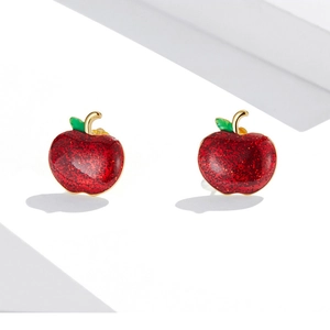 Macro shot of sparkling red apple earrings with golden stem and green leaf detail