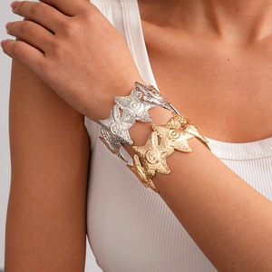 Detail of wide metallic bangle with layered wave texture and hammer finish in gold and silver