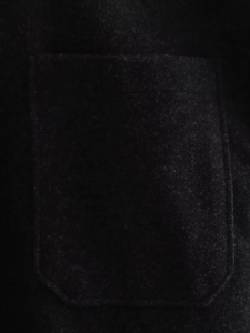 Gros plan détaillé d'une veste en laine noire avec une grande poche et texture douce