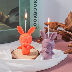 Creative rabbit baby sleeping candles in orange and purple displayed on wood