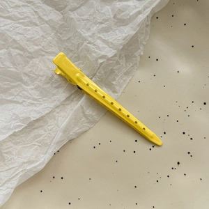 Close-up of bright yellow matte metal hair clip with hollow round hole details on the side