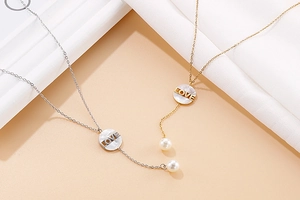 Detailed view of silver and gold pearl necklaces with circular LOVE engraved pendants