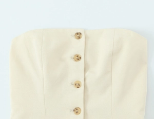 Détail de quatre boutons marbrés ambre sur un haut texturé de couleur beige