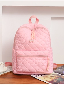 Zaino trapuntato rosa con motivo a rombi e tasca con zip su un tavolo in legno